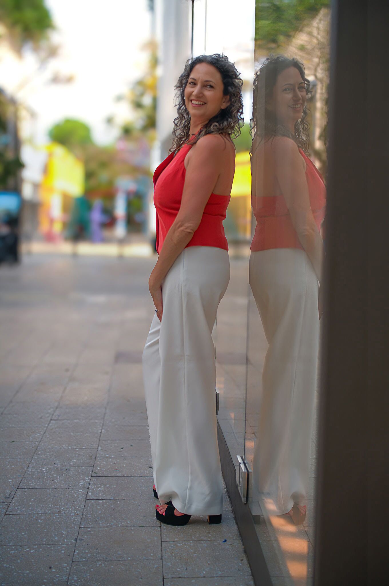 Alaina Schwartz standing beside her reflection in a storefront window